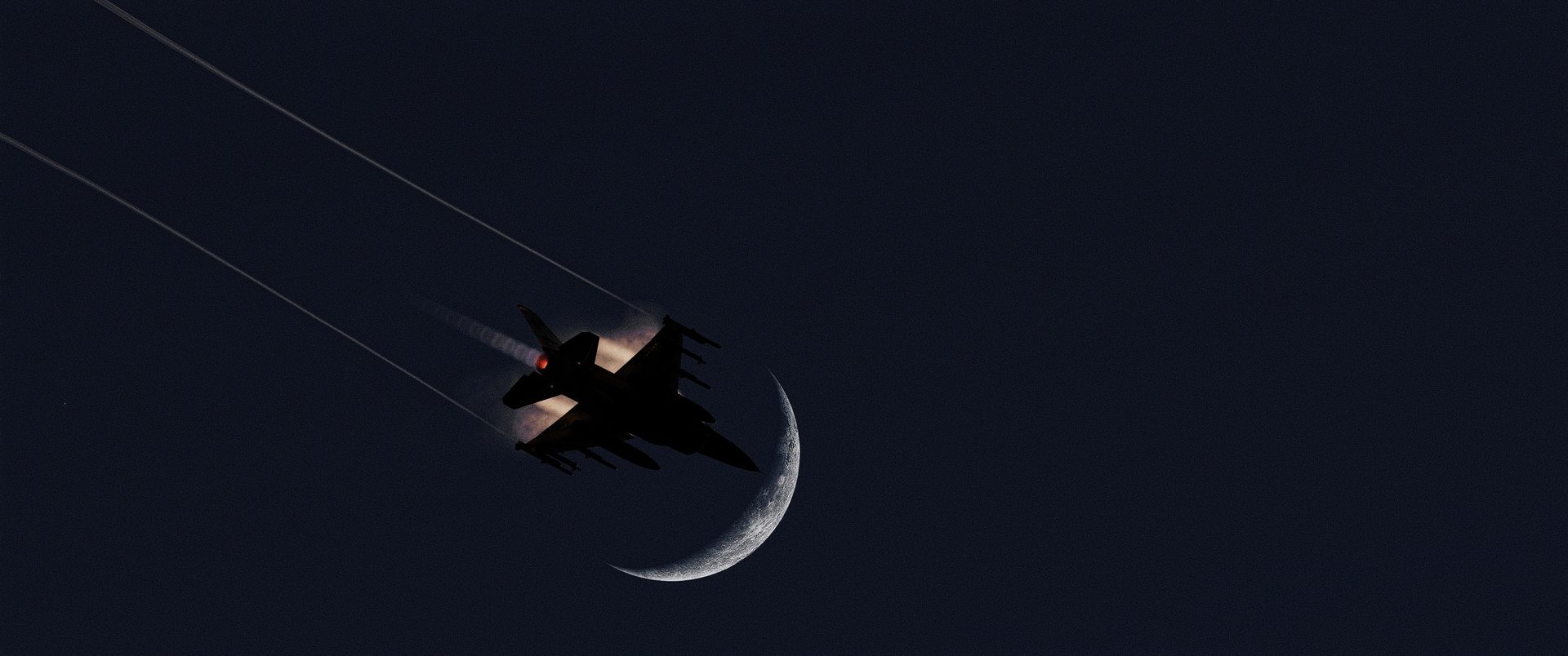 An F-16C crossing a crescent moon at night